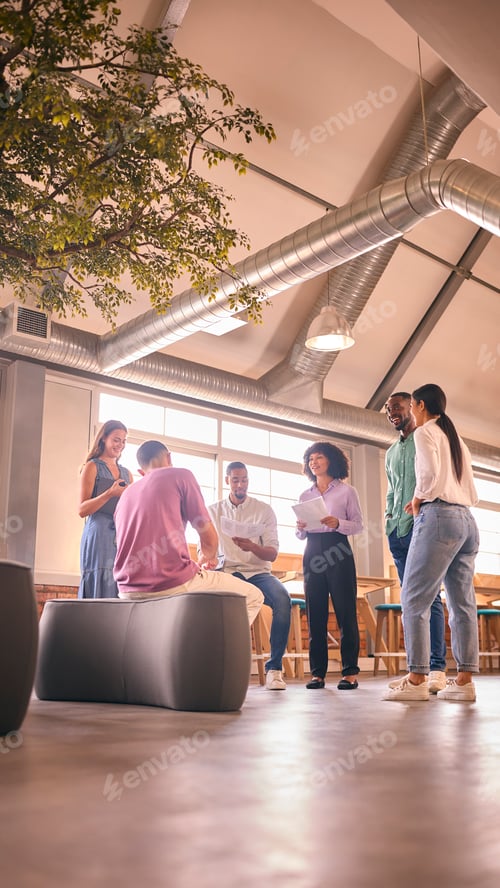 Preview: Multi-Cultural Business Team Having Informal Meeting Standing In Modern Open Plan Office Together