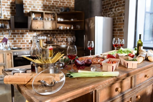Preview: kitchen table with food and drink. Fresh pizza, red wine and vegetables ready for house party