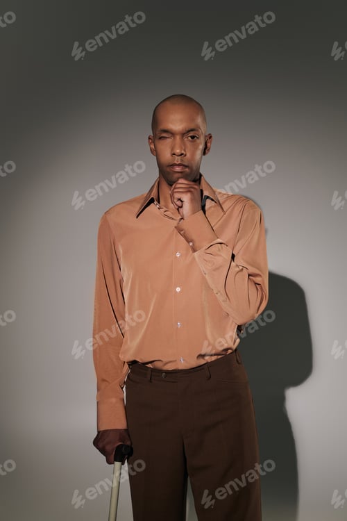 Preview: bold african american man with myasthenia gravis syndrome standing with walking cane on grey