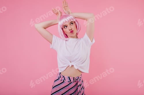 Preview: Good-looking young woman in casual stylish t-shirt fooling around in studio. Indoor portrait of rom