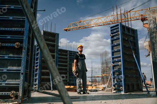 Preview: Standing with grinding machine in hands. Man in uniform is working on the construction site