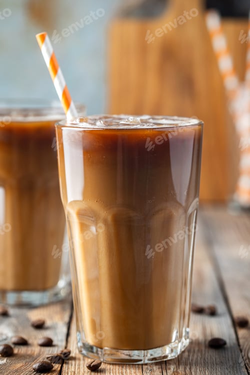 Preview: Ice coffee in a tall glass with cream poured over, coffee ice cubes and beans.