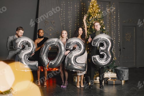 Visualização: Amigos do sexo masculino e feminino em pé com balões 2023 para a celebração do Ano Novo