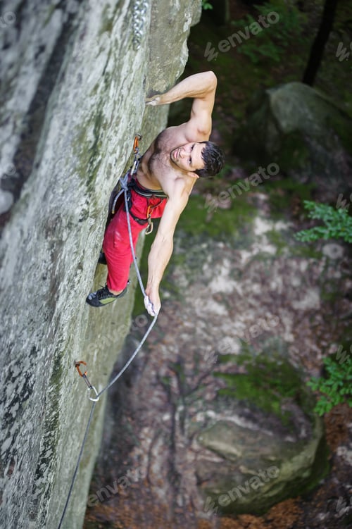 Preview: Muscular rock climber climbs on cliff wall with rope