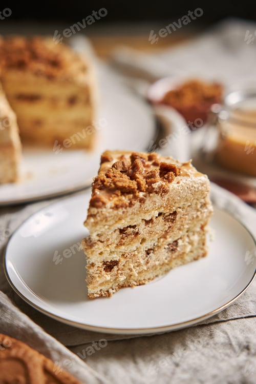 Preview: Vertical shot of a slice of delicious lotus cookie cake with caramel with cookies on the table