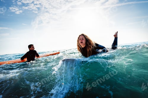 Preview: Fit couple surfing at sunset. Surfers friends having fun inside ocean. Sport and vacation concept