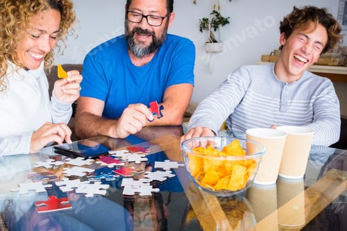 Preview: Happy real people family play together with cards at home on the table laughing and having fun.