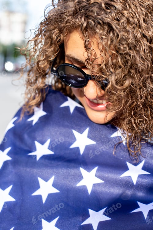 Vorschau: Nahaufnahme Porträt einer glücklichen schönen lockigen Frau mit amerikanischer Flagge