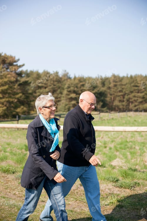 Preview: Side view of senior couple walking on field during sunny day