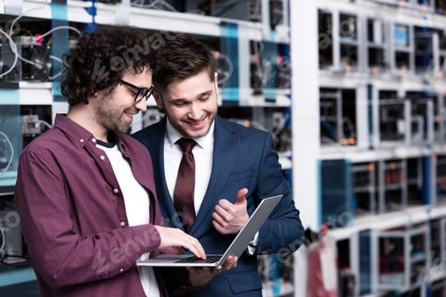 Preview: happy young businessman and computer engineer working together at ethereum mining farm