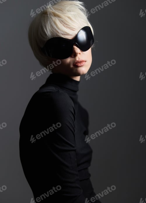 Preview: Stylish woman with short blonde hair wearing oversized black sunglasses and a sleek black outfit