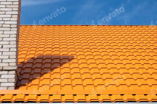 Preview: Bright orange roof of metal roofing against blue sky