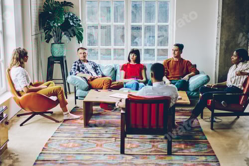 Preview: Serious adult multiracial colleagues discussing work during meeting in cozy modern office