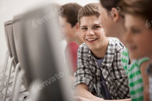 Preview: A group of young people, boys and girls, working at computer screens in class.