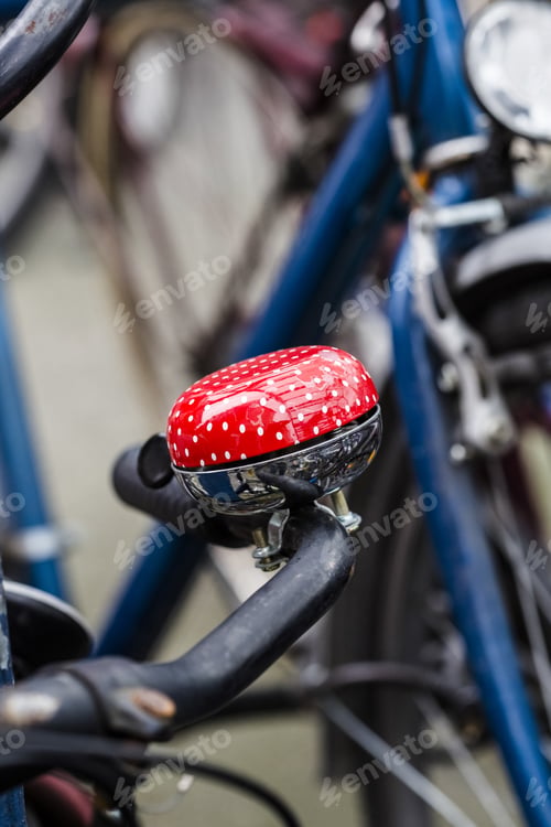 Preview: Vertical close shot of a red bicycle bell on the handle with a blurred background