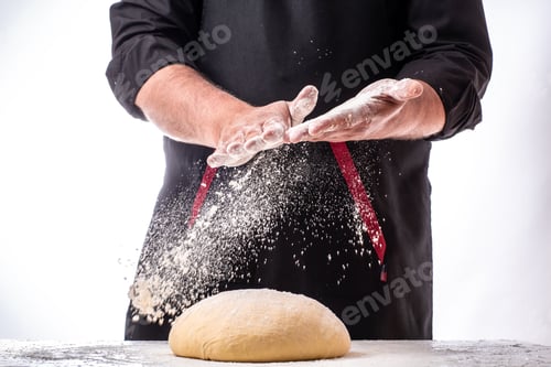Preview: Man sprinkling flour over fresh dough on kitchen table. dough on white powder covered table