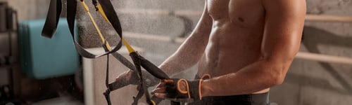 Preview: Attractive man preparing for the exercise with fitness straps at gym