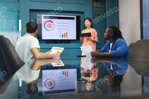 Preview: Asian woman presenting to biracial and African American men in a modern business office