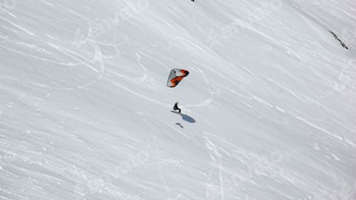 Preview: Person snowkiting down a snowy slope.