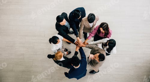 Preview: From above a quartet of diverse business professionals stands in a circle holding hands to create a