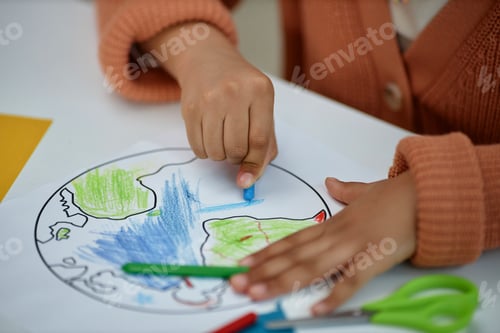 Preview: Close up of unrecognizable little girl coloring planet Earth in preschool