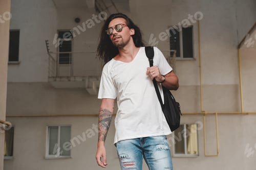 Vista previa: Hombre sobre fondo urbano con mochila y gafas de sol