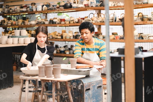 Preview: An Afro-haired potter sculpts a ceramic pot from clay on a potter's wheel. Art workshop concept