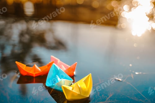 Preview: Multicolored paper boats. Colorful pink yellow blue orange ships in big spring snow puddle on