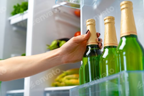 Preview: Female hand taking bottle of beer from a fridge