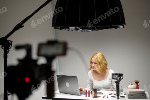 Preview: Behind the scenes young blonde woman live stream over white background studio