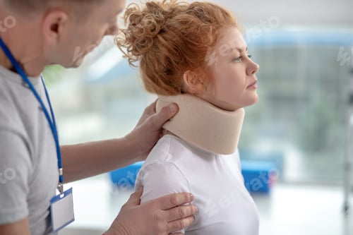 Preview: Male physiotherapist examining neck fixator of female patient