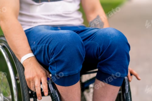 Preview: Close-up of the knees of a man with disabilities who rides a wheelchair in city park