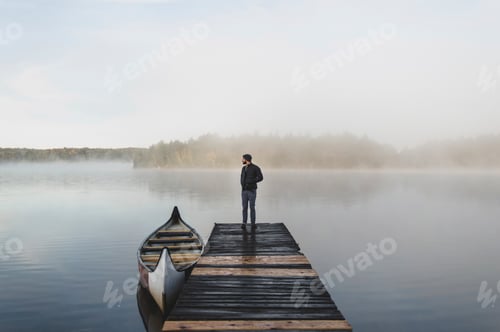 Preview: Man standing on pier, looking at view, rear view