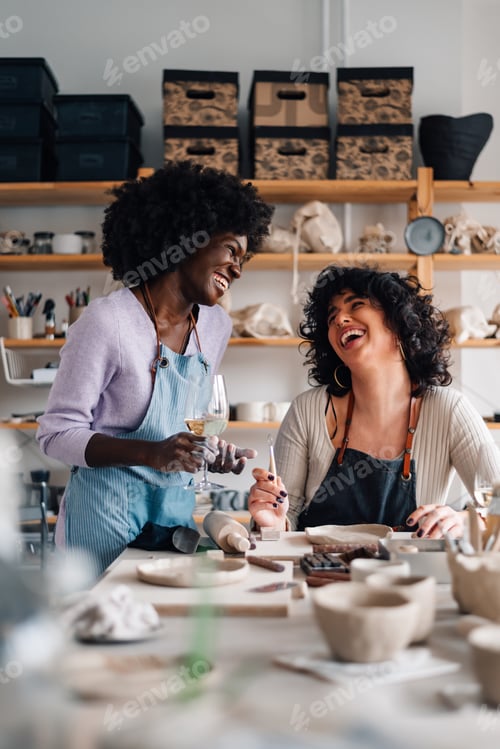 Preview: Interracial women having wine and chatting on pottery class in studio.