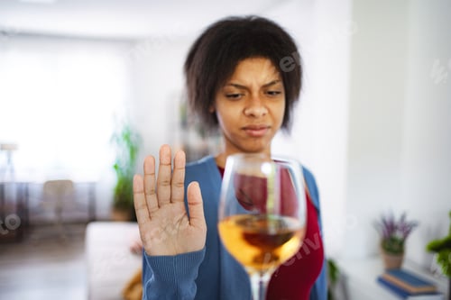 Preview: Young woman refusing a glass of wine at home