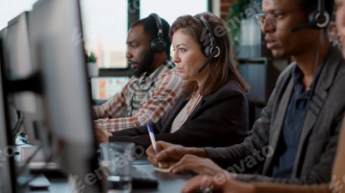Preview: Young woman using audio headset and computer at call center