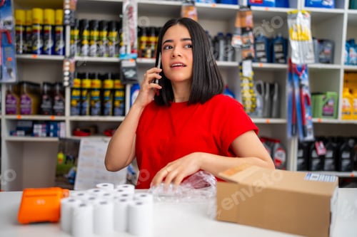 Preview: Woman talking on phone while working and handling merchandise in a small business