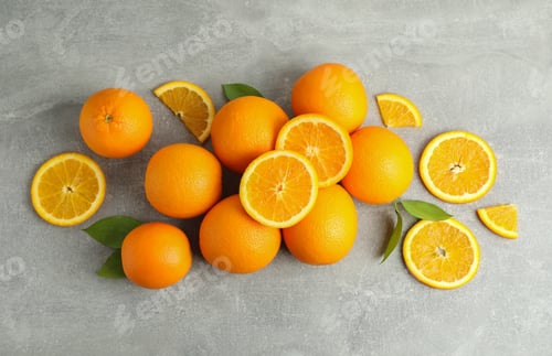 Preview: Many ripe oranges and leaves with space for text on grey table, top view