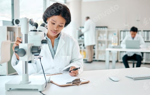 Preview: Shot of a young scientist writing notes while using a microscope in a lab