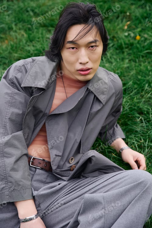 Preview: Stylish young man showcases fashion in a serene park setting during daytime
