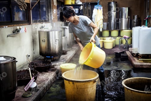 Preview: Japanese woman working in a textile plant dye workshop, pouring hot water into yellow plastic