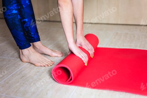 Preview: Close up of a woman hands is rolling up exercise mat and preparing to doing yoga.