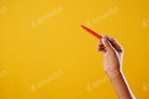 Preview: holding a red color pencils against yellow background