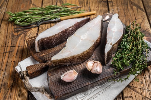 Preview: Atlantic halibut fish, raw steaks on wooden board with herbs. Wooden background. Top view