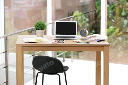 Preview: Designer's workplace with laptop and paint color palette samples on table