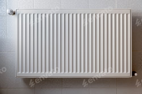 Preview: White metal heating radiator mounted on a wall in room interior.
