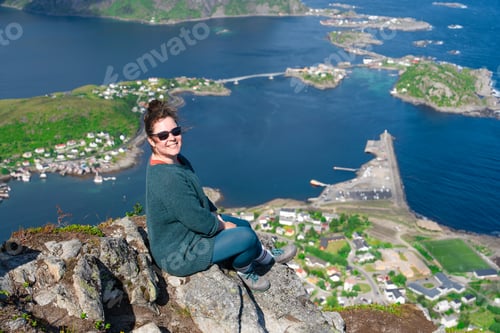 Preview: Alone happy woman hiker enjoys the view on cliff edge of lofoten islands, in Norway, Reinebringen