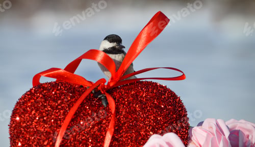 Chickadee Perched on a Heart with Red Ribbon