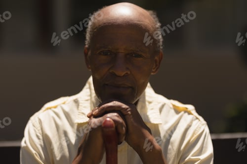 Preview: Front view of senior man hands leaning on a cane while sitting on bench on sunny day in garden