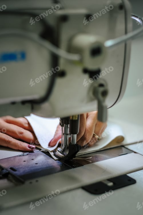 Preview: Vertical shot of female hands using a sewing machine